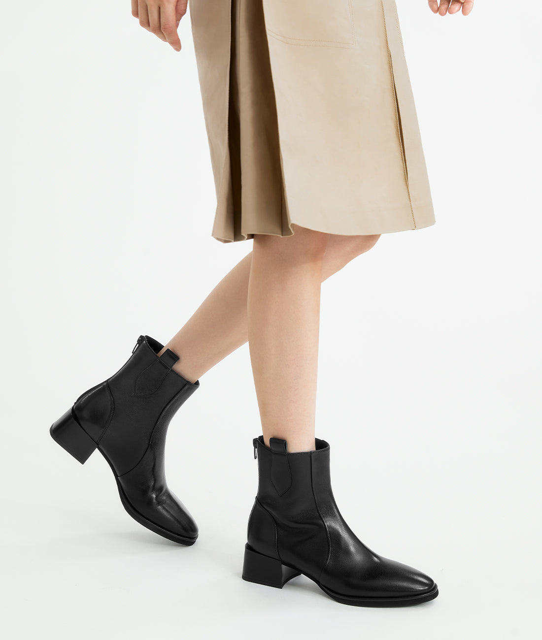 A model showcasing the stylish black lambskin ankle boots, featuring a modern almond toe and sturdy block heel