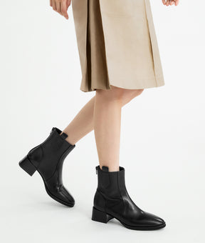 A model showcasing the stylish black lambskin ankle boots, featuring a modern almond toe and sturdy block heel