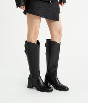A model showcasing the winter-ready black riding boots, featuring a 7cm block heel, warm lining, and sleek profile