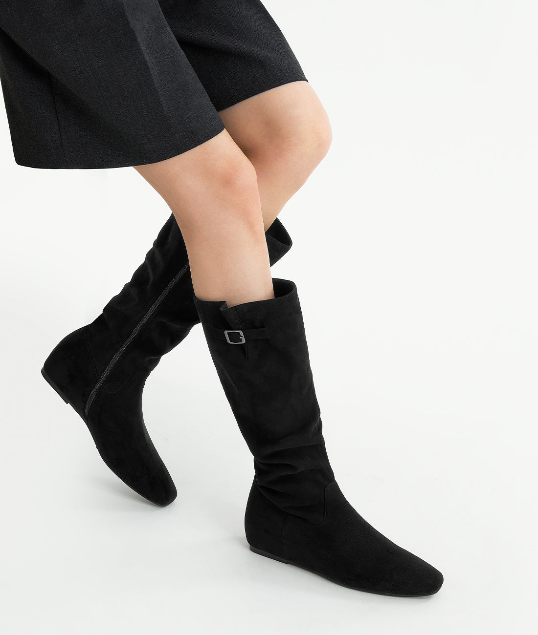 Model shot from the side wearing the black suede slouch boots with side buckle